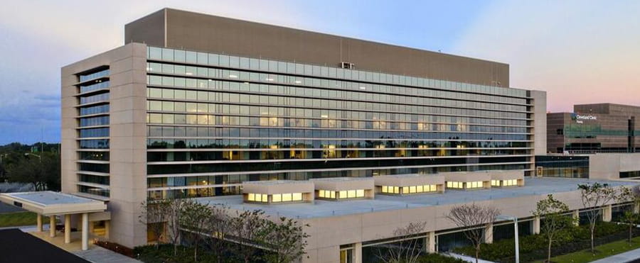 Exterior view of a large, modern multi-story building with a glass facade and covered entrance