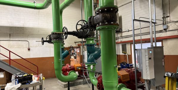 Large green industrial pipes with valve wheels connected to pumps in a mechanical room for Kroger Chilled Water Plant Replacement