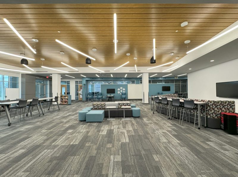 Indian Hill Bond Levy learning space with modular seating, high tables with stools, wood panel ceiling, and linear lighting