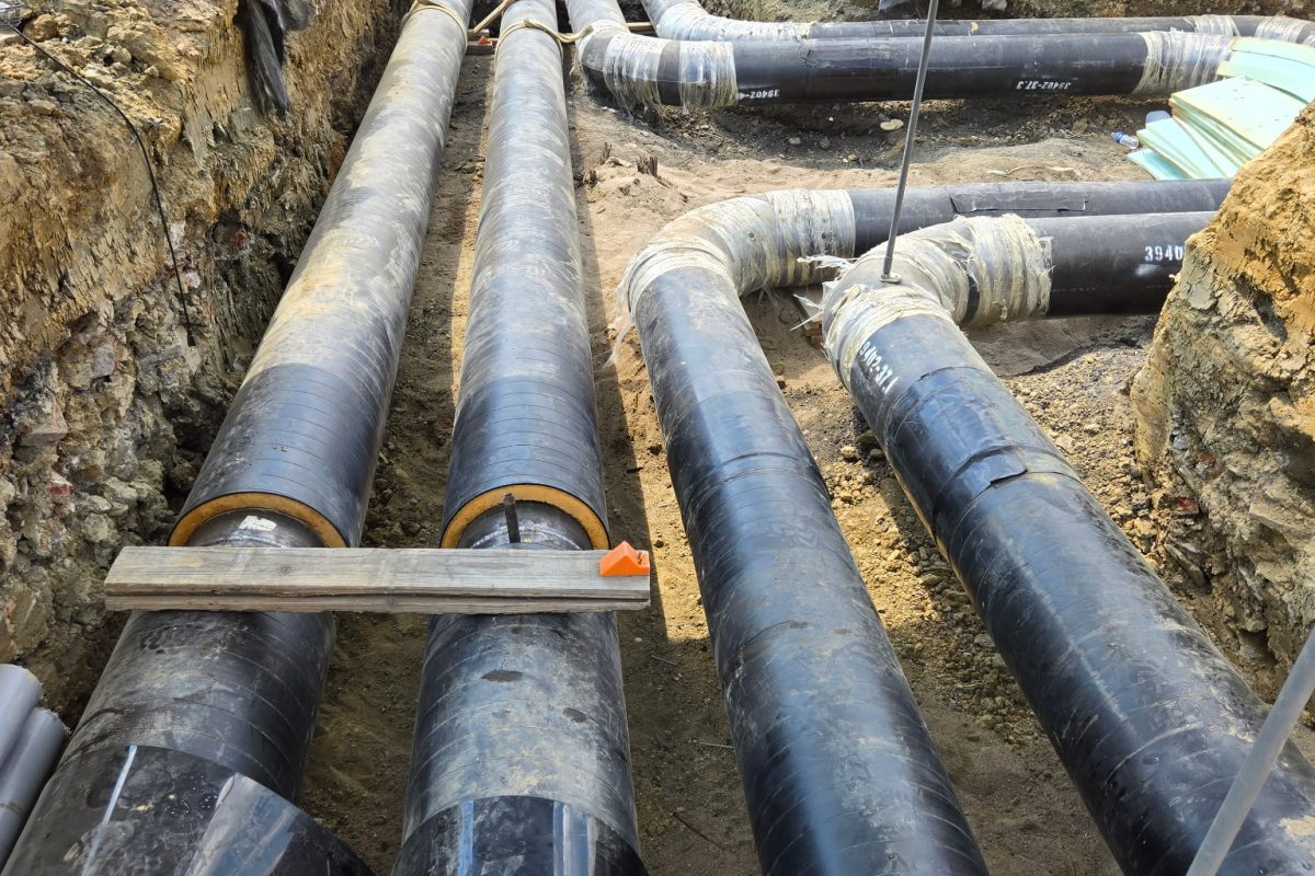 Large insulated utility pipes laid in an excavated trench at Xavier University College of Medicine